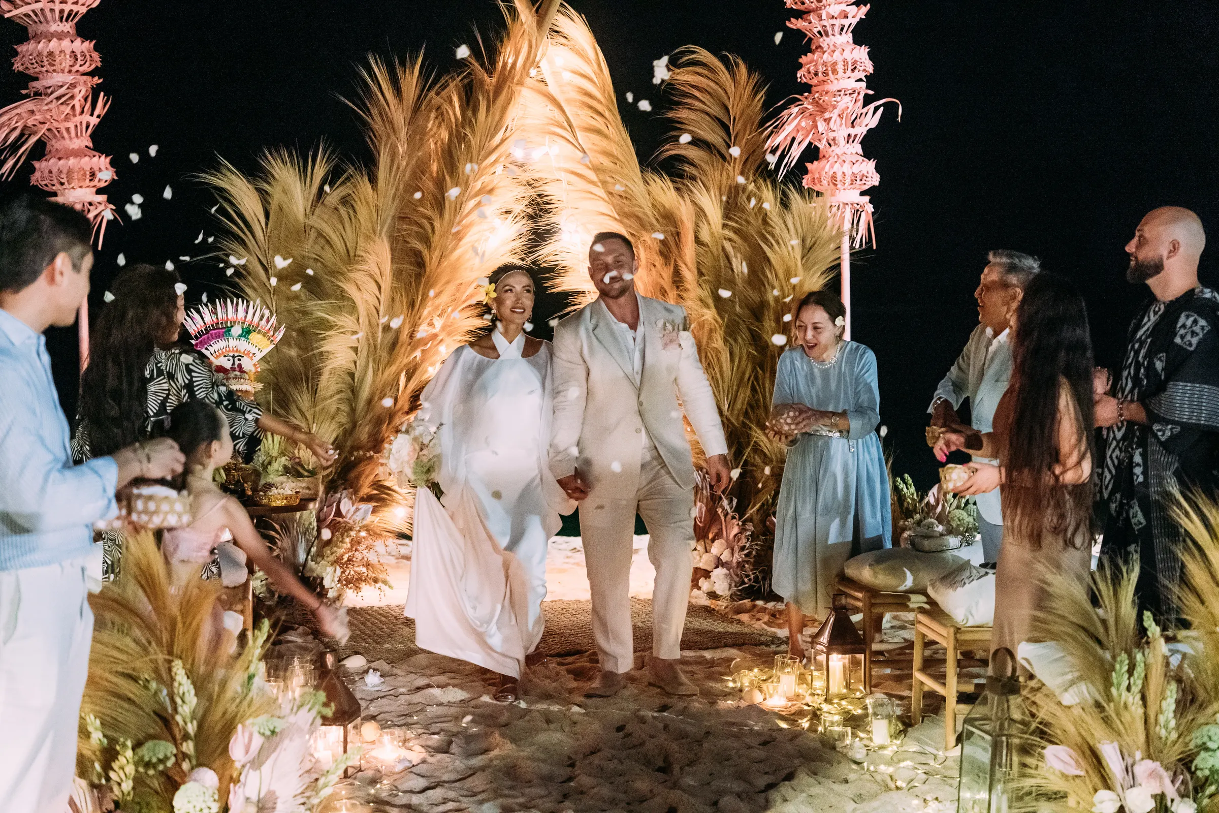 Bride and groom walking down a candlelit beach aisle at their Bali wedding, composed by ICE