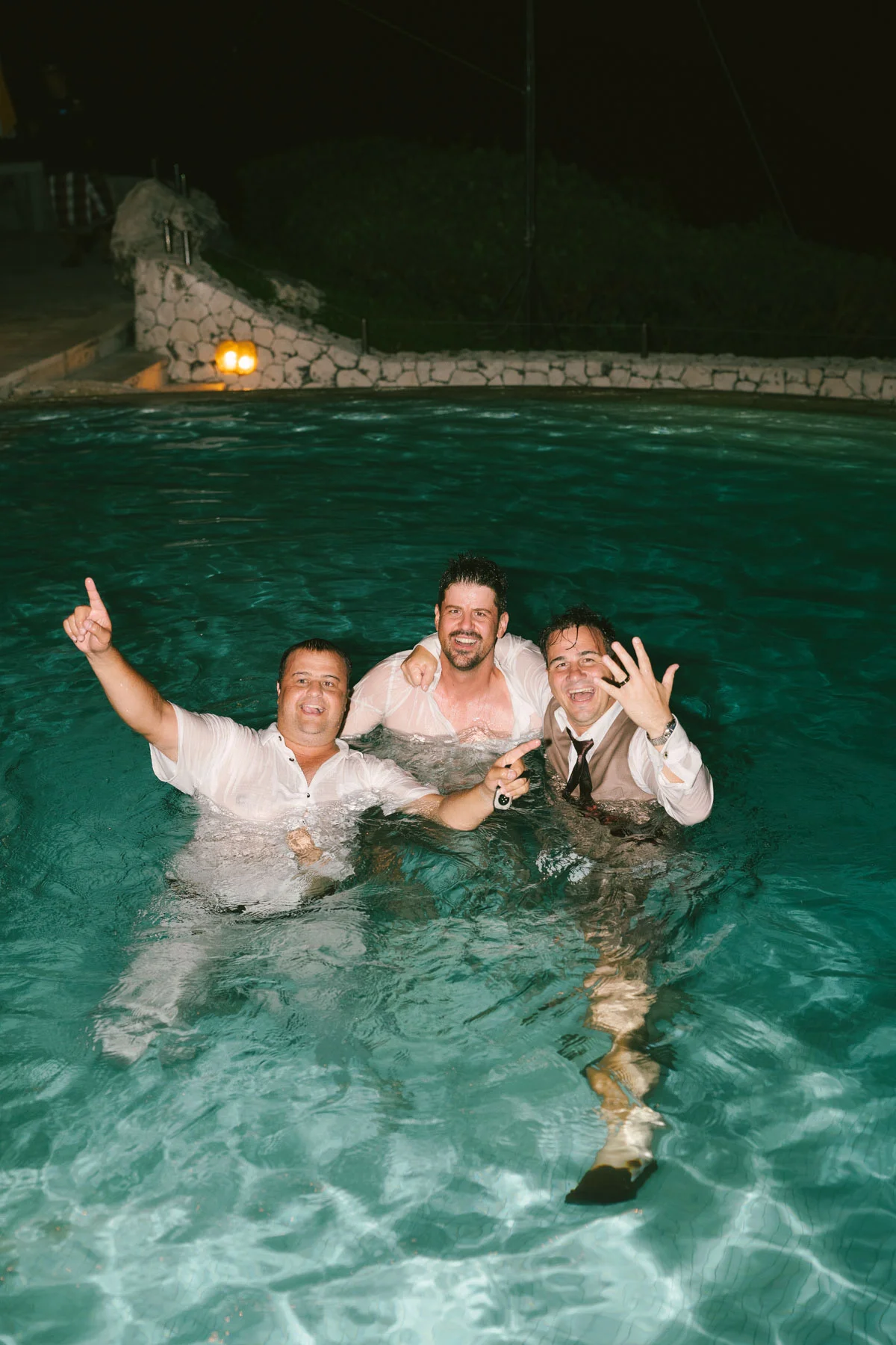 Groomsmen celebrating at the infinity pool after dark