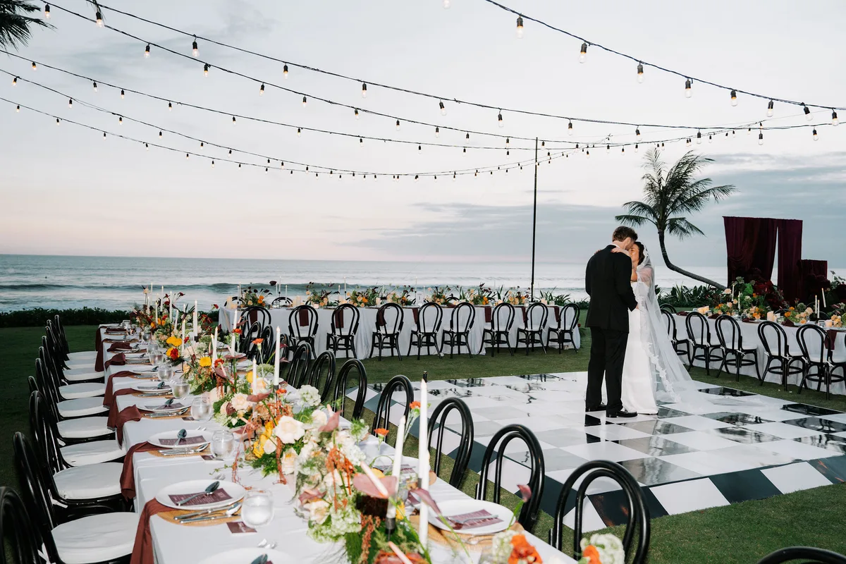 Kersten and William share their first dance on a checkered floor at sunset by the sea