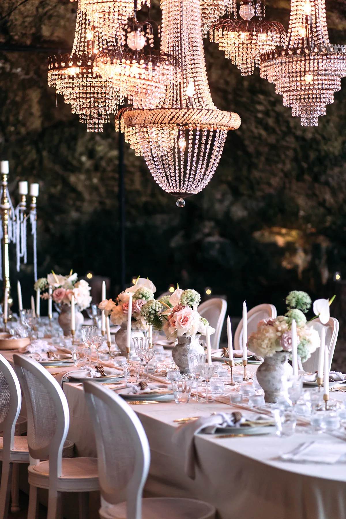 Crystal chandeliers above a reception table of pastel florals