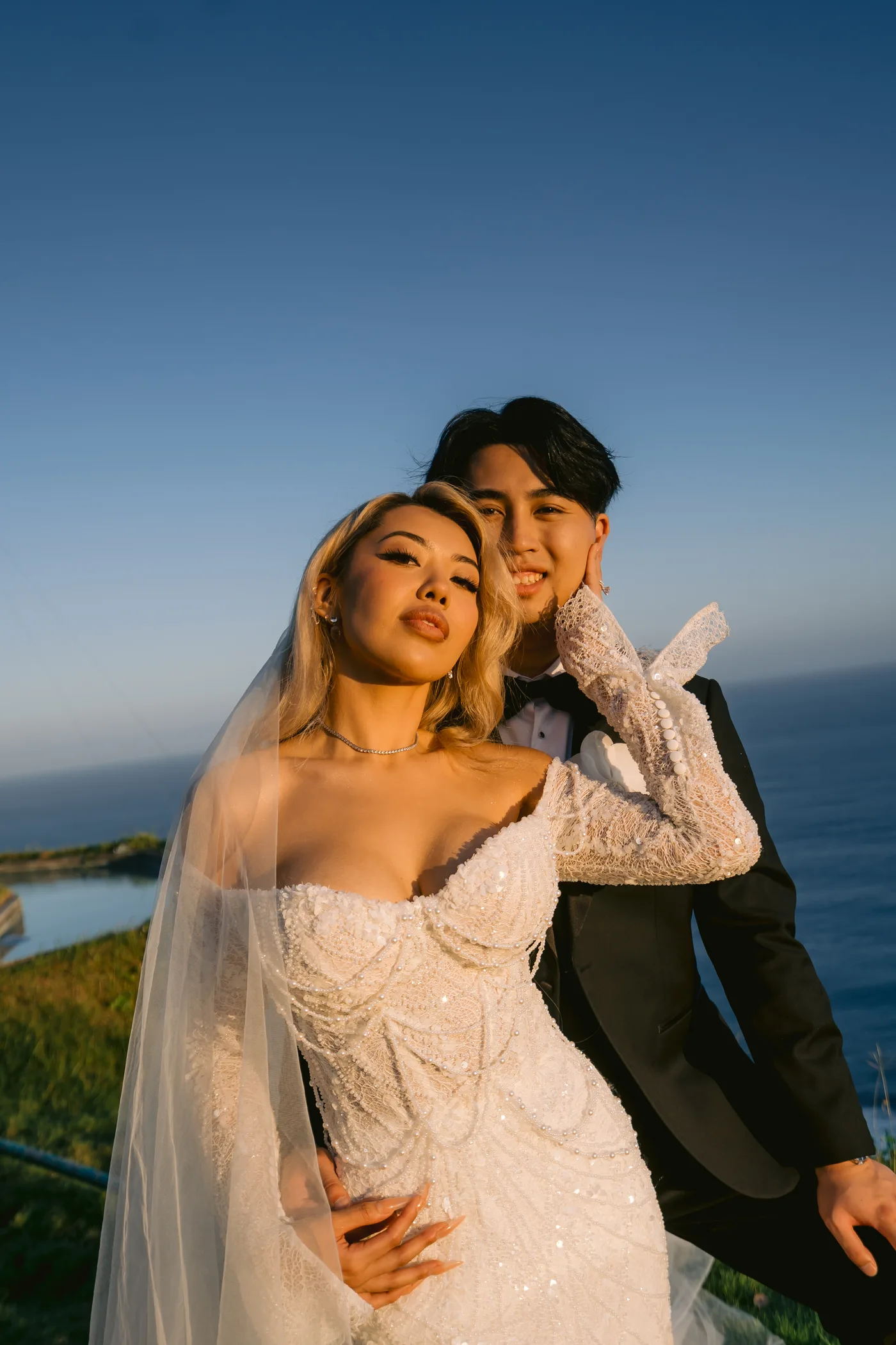 A close portrait of the newlyweds against a clear blue sky and ocean