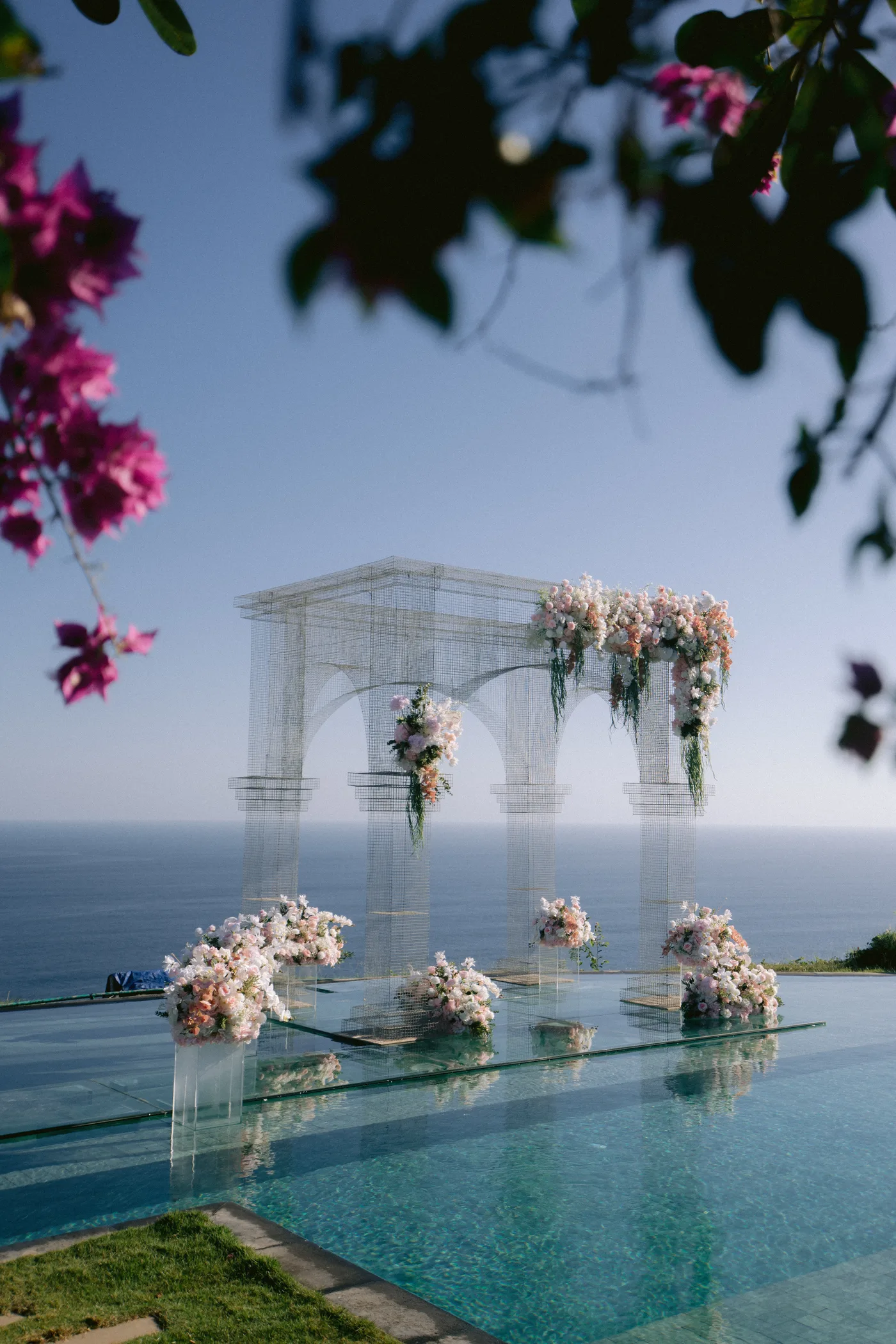 Pink bougainvillea frames the ceremony arch overlooking the sea