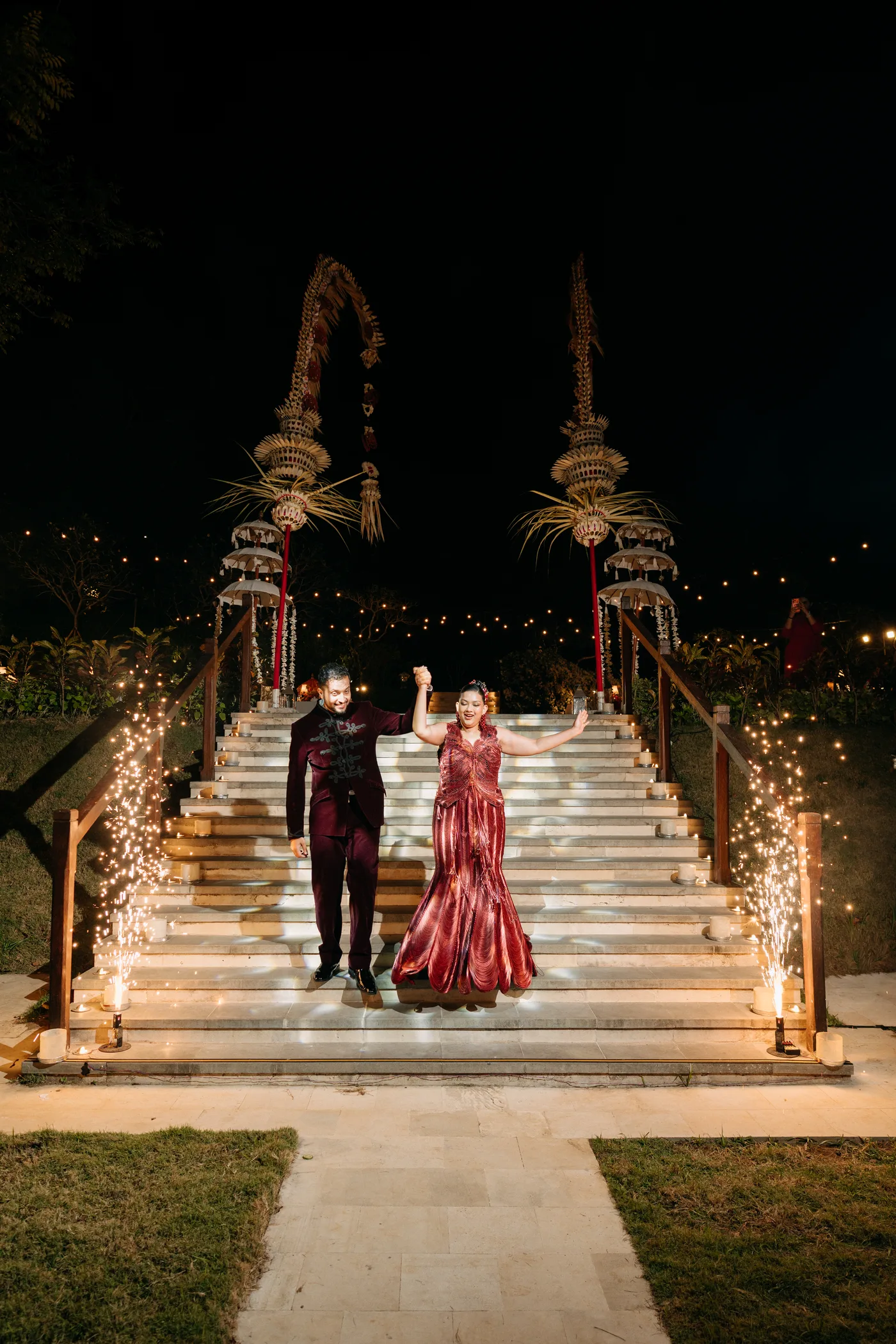 Bride and groom celebrating on an illuminated staircase lined with sparklers