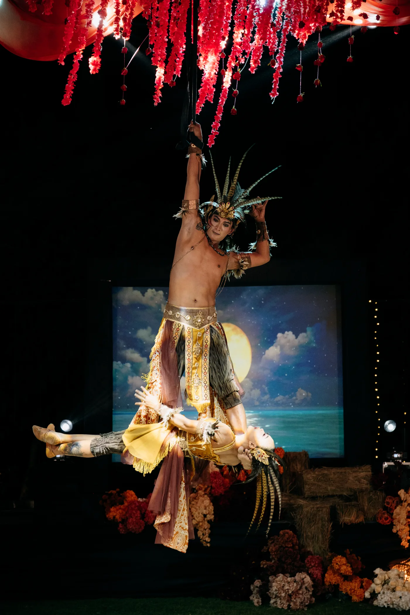Aerial silk performers in feathered headdresses above the reception